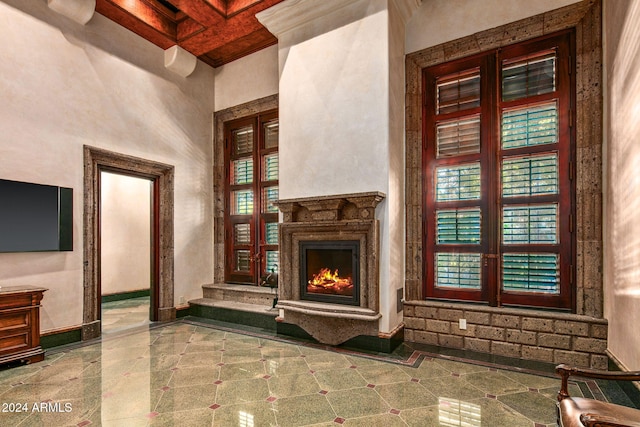 unfurnished living room with a high ceiling, beamed ceiling, coffered ceiling, and ornamental molding