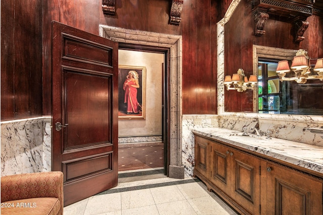 bathroom with wood walls, vanity, and tile patterned floors