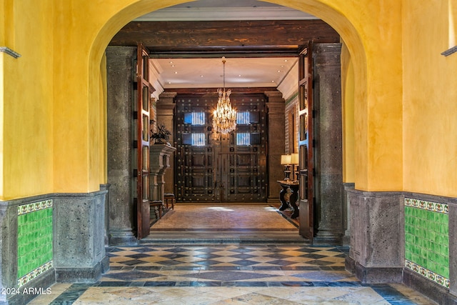 hall with a notable chandelier and ornamental molding