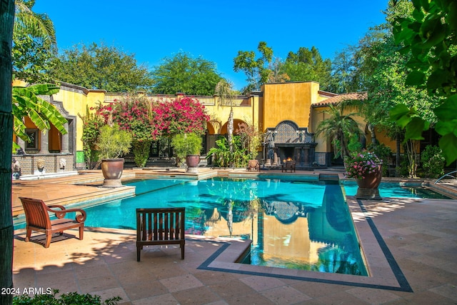 view of swimming pool featuring an outdoor fireplace and a patio