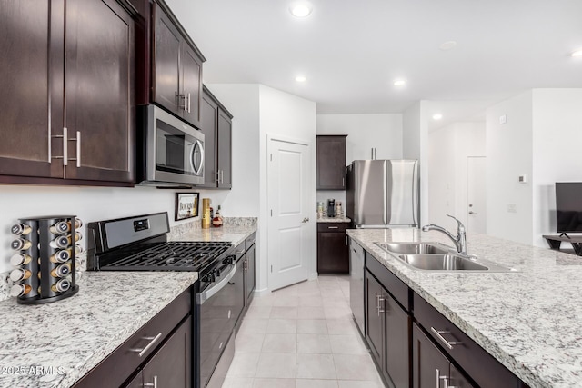 kitchen featuring appliances with stainless steel finishes, sink, light tile patterned floors, light stone countertops, and dark brown cabinets