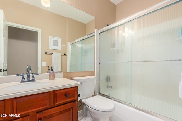 full bathroom featuring combined bath / shower with glass door, vanity, and toilet