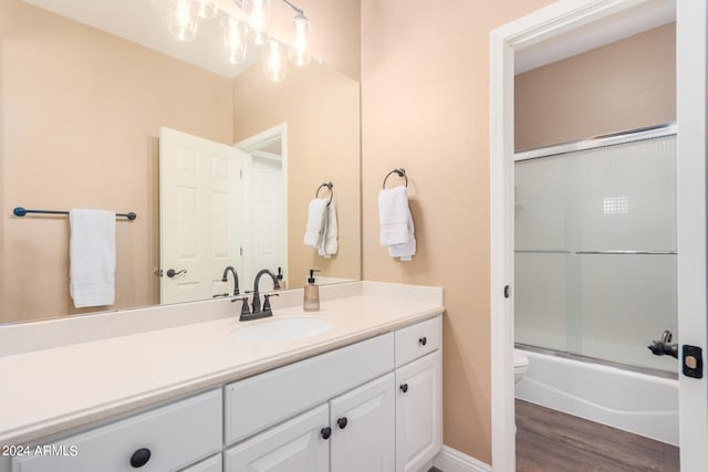 full bathroom with vanity, hardwood / wood-style floors, enclosed tub / shower combo, and toilet