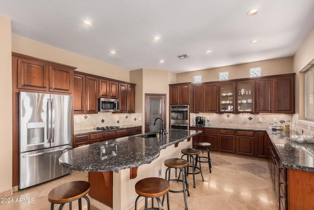 kitchen with a breakfast bar area, a center island with sink, appliances with stainless steel finishes, and sink