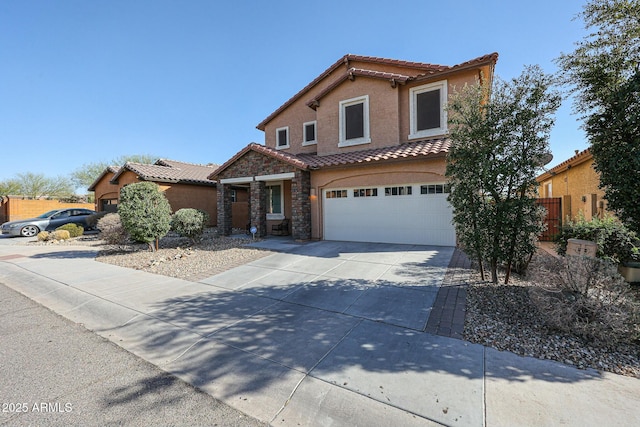 mediterranean / spanish house featuring an attached garage, a tile roof, concrete driveway, stone siding, and stucco siding