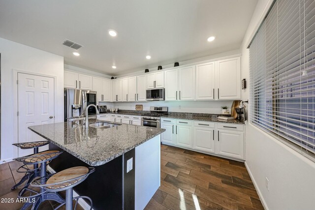 1713 W Cottonwood Ln, Phoenix, AZ 85045 - kitchen with stainless steel appliances, visible vents, wood tiled floor, a sink, and a kitchen breakfast bar