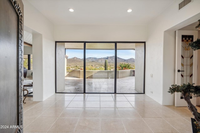 empty room with a mountain view, light tile patterned floors, and a healthy amount of sunlight