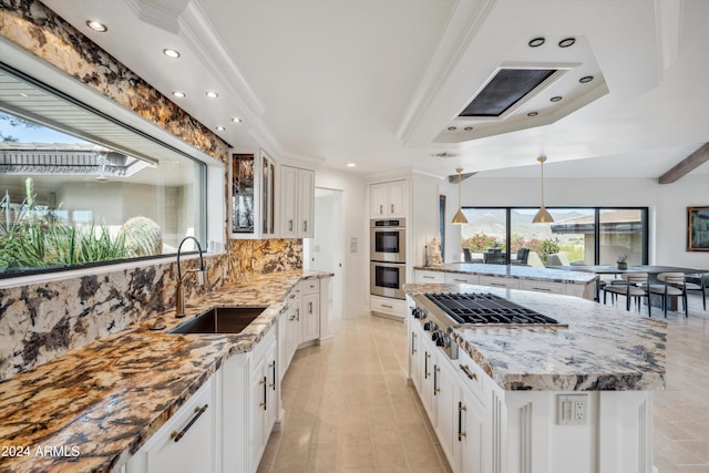 kitchen with light stone countertops, sink, backsplash, white cabinets, and appliances with stainless steel finishes