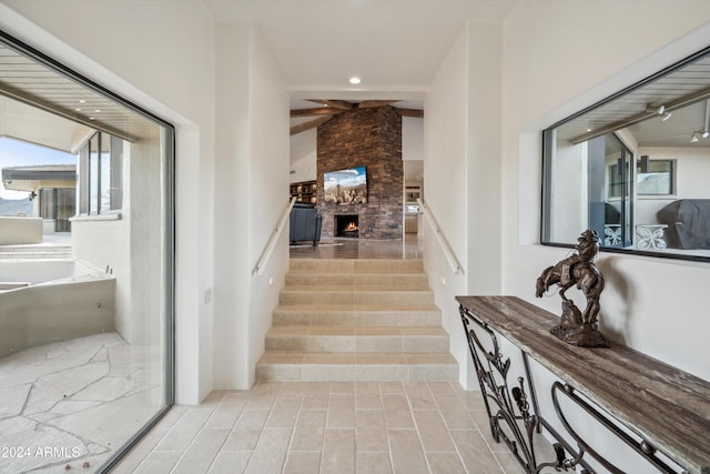 staircase with a fireplace, beam ceiling, and wood-type flooring