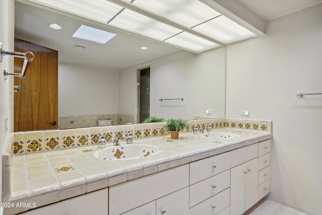 bathroom with tile patterned floors, vanity, toilet, and a skylight