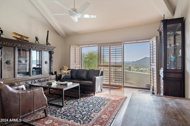 living room with a mountain view, wood-type flooring, vaulted ceiling with beams, and ceiling fan