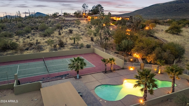 pool at dusk with a mountain view and tennis court