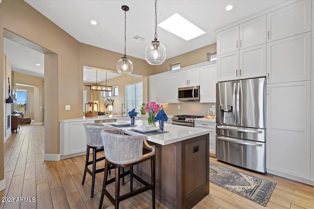 kitchen featuring a healthy amount of sunlight, appliances with stainless steel finishes, light hardwood / wood-style flooring, and white cabinets