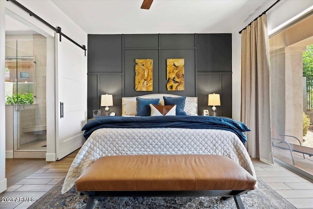 bedroom featuring connected bathroom, ceiling fan, light wood-type flooring, and a barn door