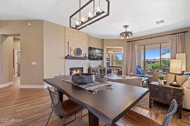 dining room with a stone fireplace and wood-type flooring