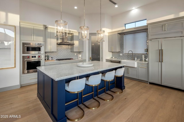 kitchen with a sink, stainless steel appliances, a center island, decorative backsplash, and a kitchen bar