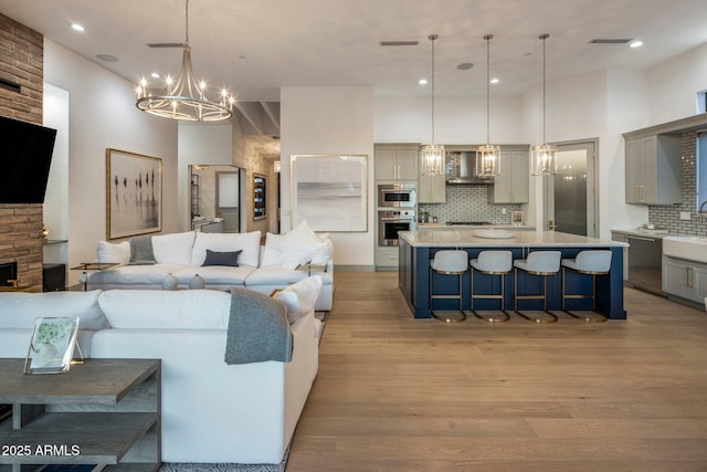 living area with a chandelier, light wood finished floors, a towering ceiling, and recessed lighting