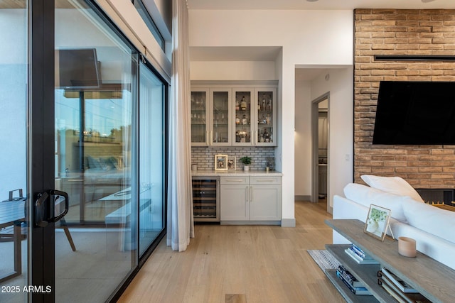 indoor bar featuring beverage cooler, light wood-style floors, and backsplash