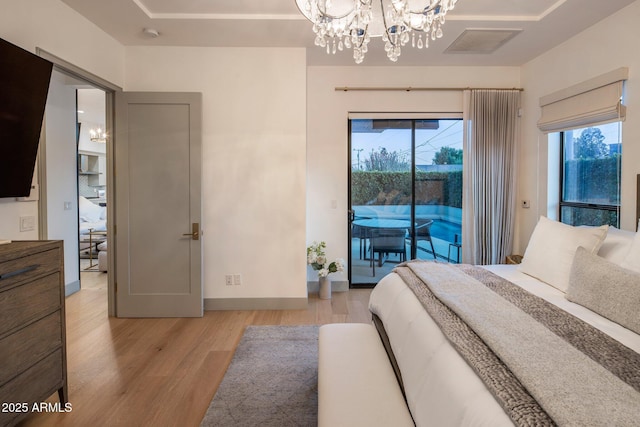 bedroom with a chandelier, light wood finished floors, access to exterior, and multiple windows