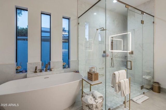 full bath with a freestanding bath, a stall shower, tile patterned floors, and tile walls