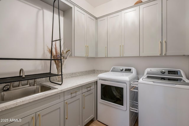 clothes washing area with separate washer and dryer and cabinet space