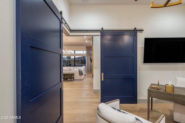 interior space featuring a barn door, light wood-type flooring, and a chandelier