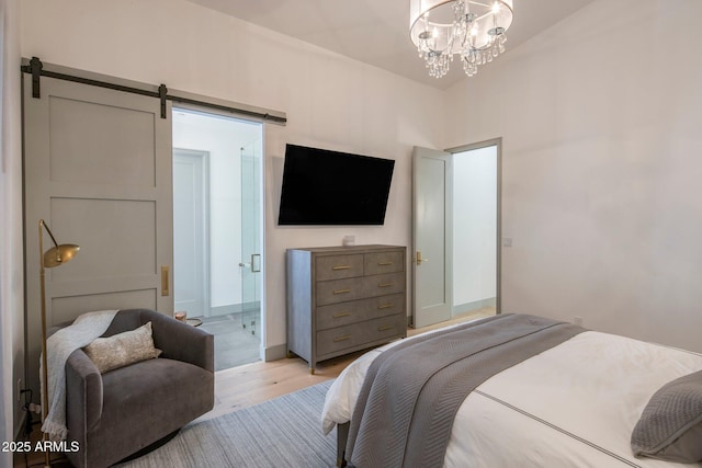 bedroom featuring light wood-style flooring, a barn door, and a chandelier