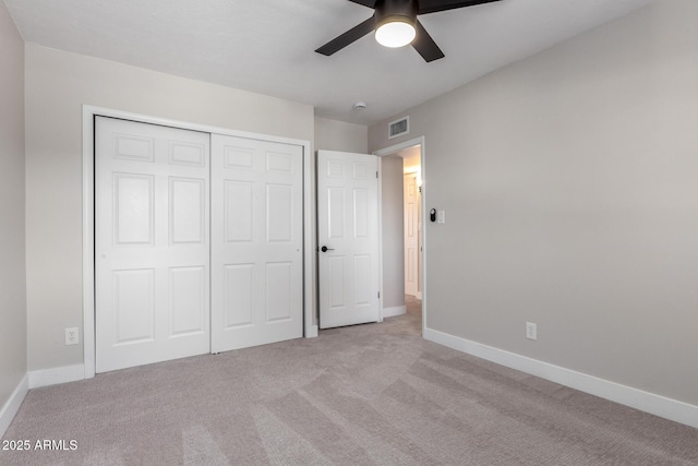 unfurnished bedroom featuring light carpet, ceiling fan, and a closet