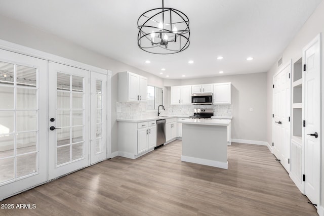 kitchen featuring appliances with stainless steel finishes, decorative light fixtures, sink, white cabinets, and french doors