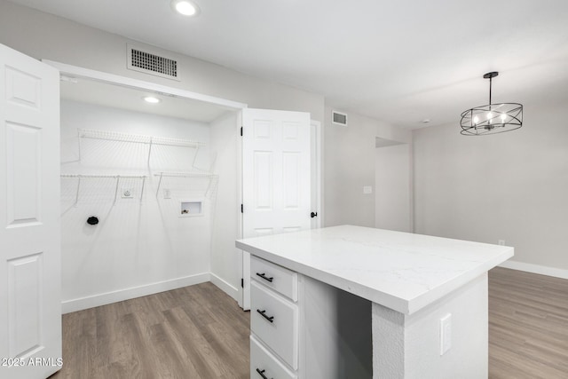 washroom featuring an inviting chandelier, hookup for a washing machine, and light hardwood / wood-style flooring