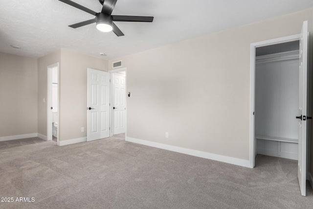 unfurnished bedroom featuring ceiling fan, light colored carpet, a spacious closet, and a closet