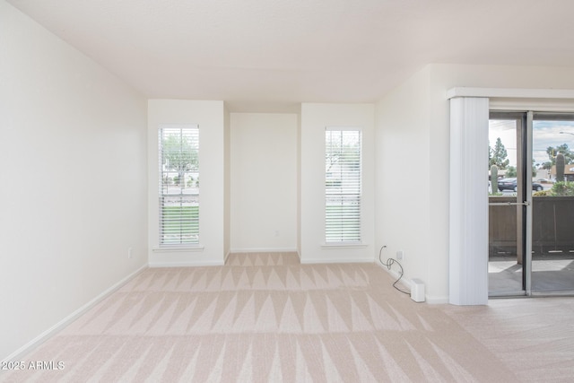 carpeted empty room with a wealth of natural light and baseboards