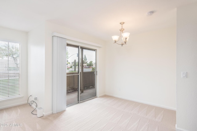 unfurnished room with a notable chandelier, plenty of natural light, and light carpet