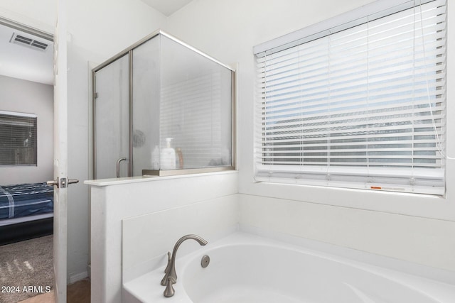 bathroom with shower with separate bathtub and a healthy amount of sunlight