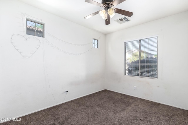 spare room featuring ceiling fan and dark carpet