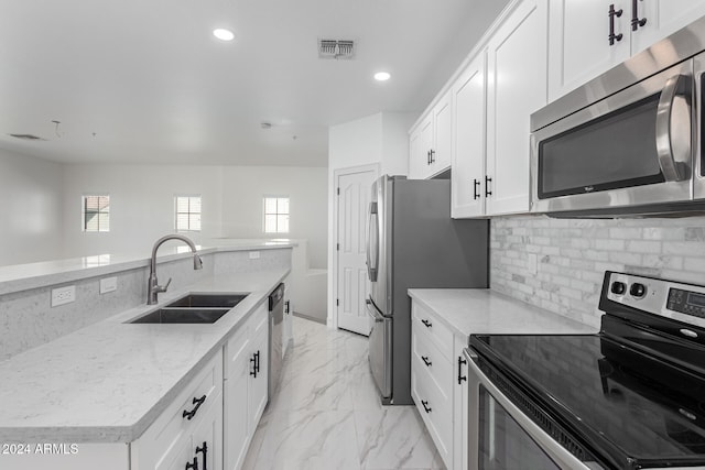 kitchen with white cabinets, backsplash, light stone countertops, sink, and stainless steel appliances