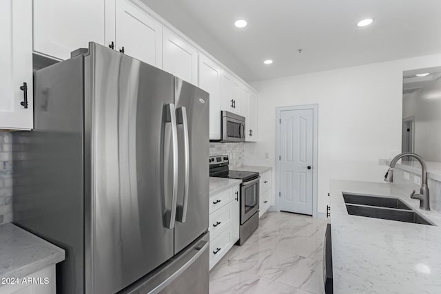 kitchen with white cabinetry, light stone counters, appliances with stainless steel finishes, and sink