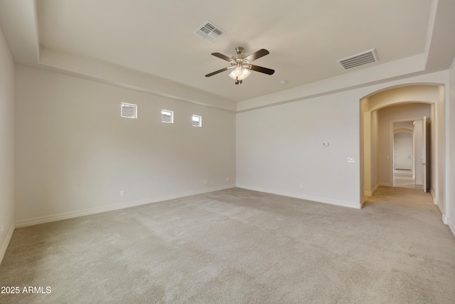 carpeted empty room featuring a tray ceiling and ceiling fan