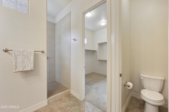 bathroom with tiled shower, tile patterned floors, and toilet