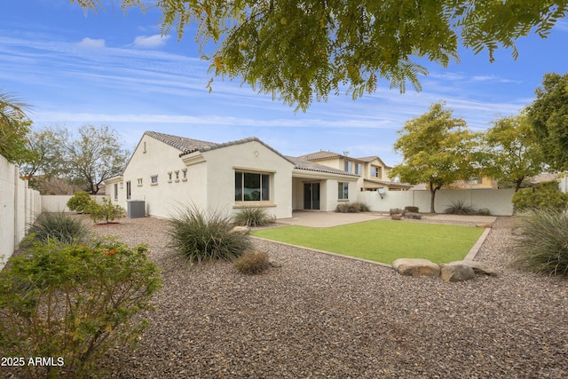 rear view of house with central AC unit, a lawn, and a patio