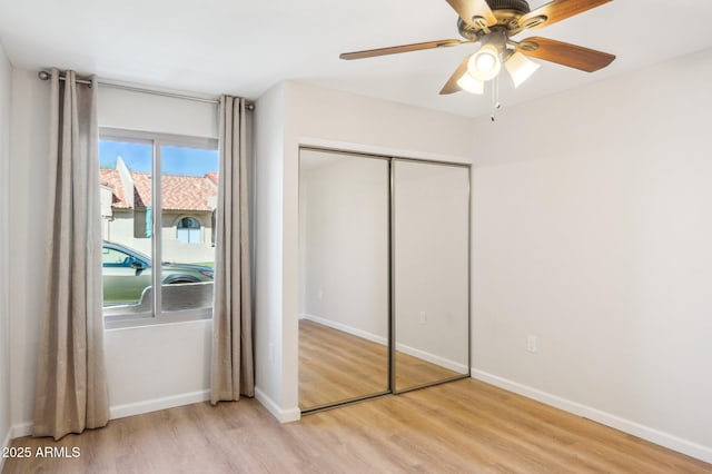 unfurnished bedroom featuring a closet, baseboards, and light wood finished floors