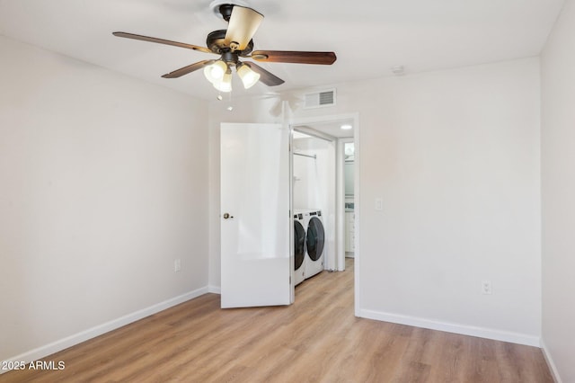 spare room with washing machine and dryer, visible vents, light wood finished floors, and baseboards