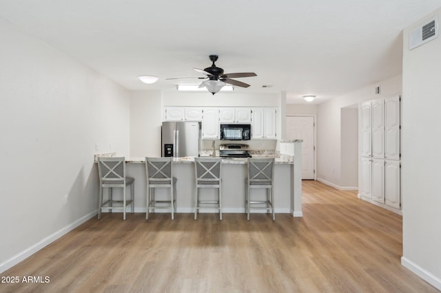 kitchen with white cabinetry, a peninsula, a breakfast bar area, and stainless steel appliances