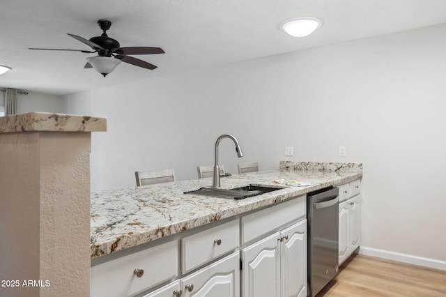 kitchen with baseboards, dishwasher, light wood-type flooring, a ceiling fan, and a sink