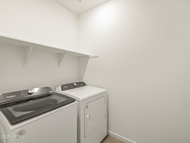 clothes washing area featuring washing machine and dryer, laundry area, and baseboards