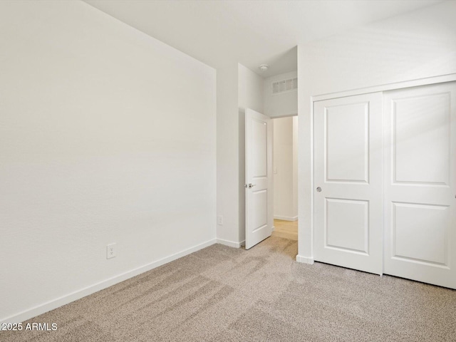 unfurnished bedroom with a closet, carpet flooring, visible vents, and baseboards