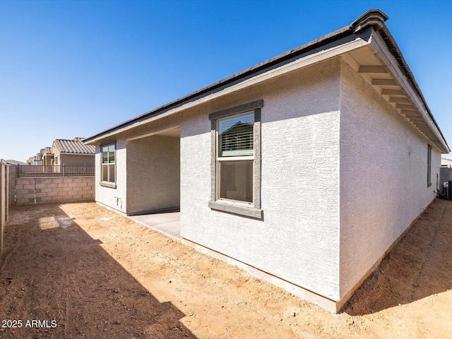 view of property exterior with fence and stucco siding