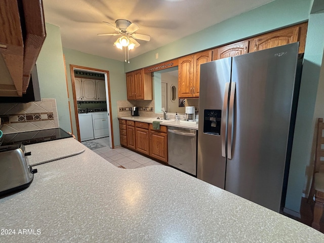 kitchen with appliances with stainless steel finishes, tasteful backsplash, ceiling fan, light tile patterned floors, and washer and dryer