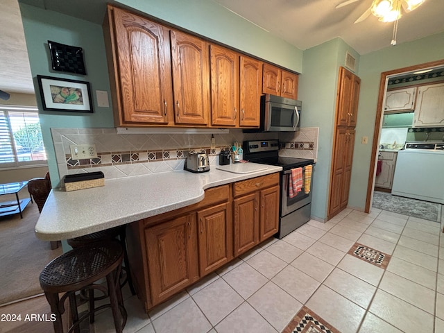 kitchen featuring appliances with stainless steel finishes, light tile patterned floors, backsplash, and washer / dryer