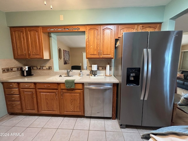 kitchen featuring stainless steel appliances, sink, tasteful backsplash, and light tile patterned floors